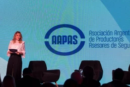 Mujer sobre escenario de Asociación Argentina de Productores Asesores de Seguros