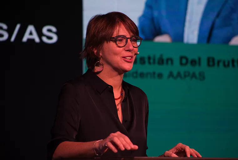 Mujer sobre escenario de Asociación Argentina de Productores Asesores de Seguros