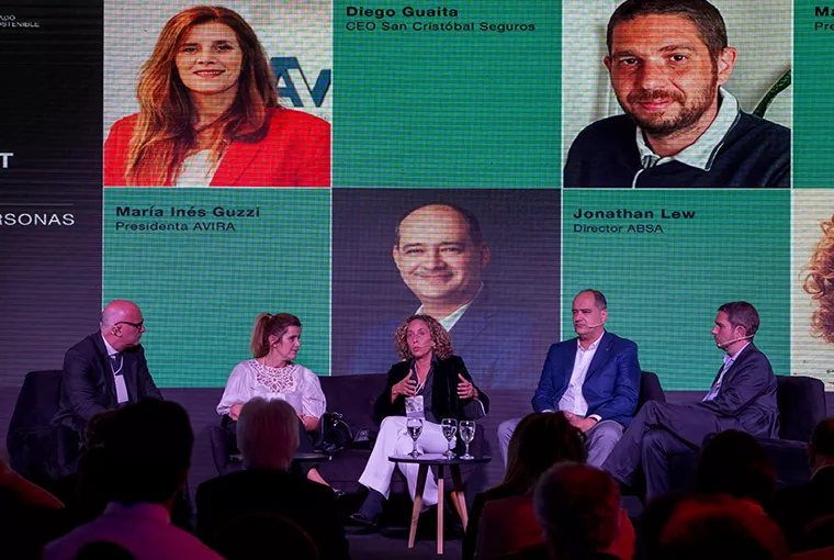 Hombres y mujeres sobre escenario de Asociación Argentina de Productores sentados sobre el escenario Asesores de Seguros