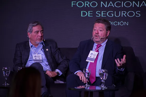 Dos hombres hablando en una conferencia de prensa de seguros